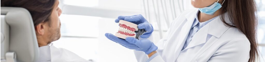 pretty dentist showing her patient jaw model.jpg s1024x1024wisk20cRkVx0guiBxadTCOsZRt2g0AoJBmvAtqL2L7HH5QKnWk